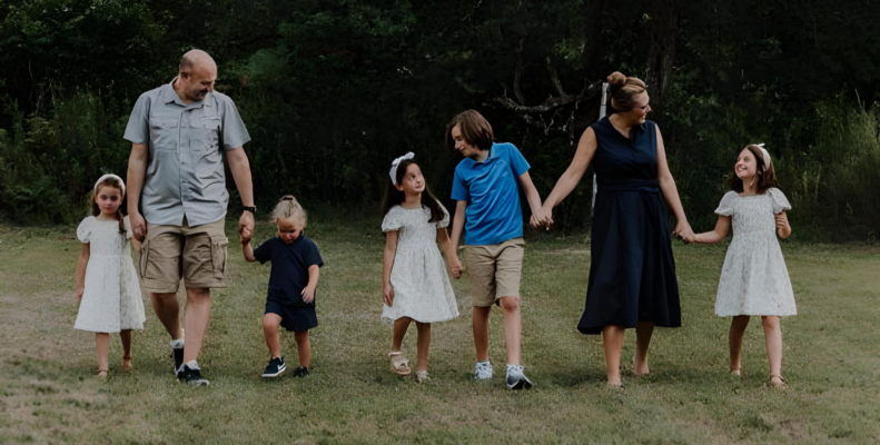 A happy family picture with five kids, who are happy and together holding hands.