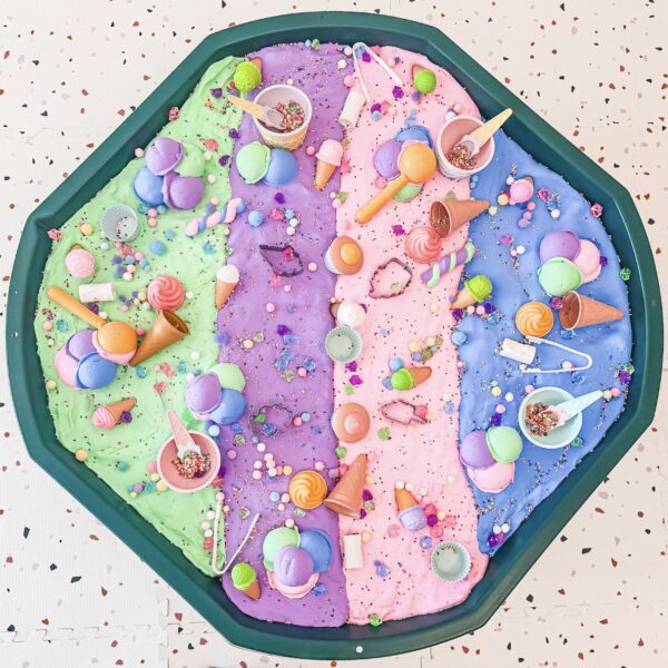 Pastel-colored ice cream mosaic with scoops, cones, and sprinkles on a green tray, arranged in four sections of green, purple, pink, and blue.